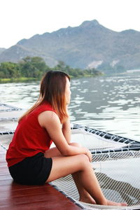 Woman sitting on net by lake
