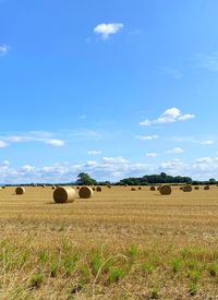 Hay bales on field against sky