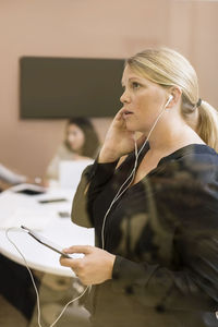 Businesswoman communicating on digital tablet using headphones in office