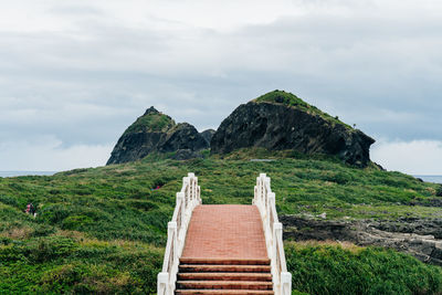 View of footbridge leading towards rock mountain