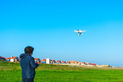 Rear view of person photographing against clear blue sky