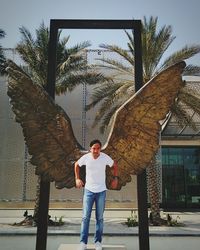 Full length of young man standing by palm tree