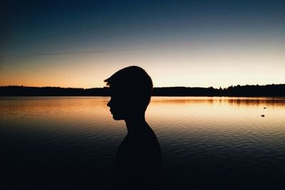 Silhouette of woman standing by lake