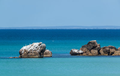 Rocks in sea against blue sky