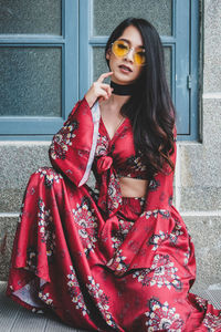 Portrait of beautiful young woman wearing sunglasses standing outdoors