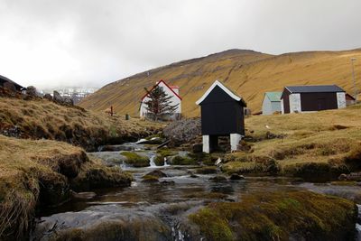 Water flowing through rocks by building against sky