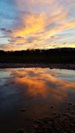 Scenic view of lake against cloudy sky during sunset