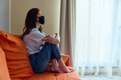 Young woman wearing protective face mask at home