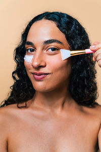 Close-up of young woman applying make-up