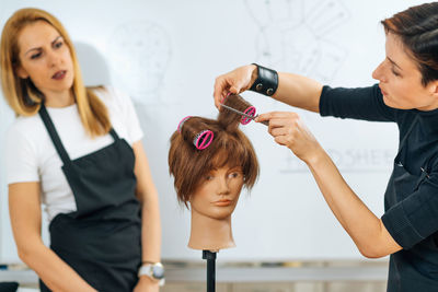Hairstylist school - female adult student practicing how to make hair styling with hair roller