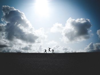 Silhouette people on field against sky