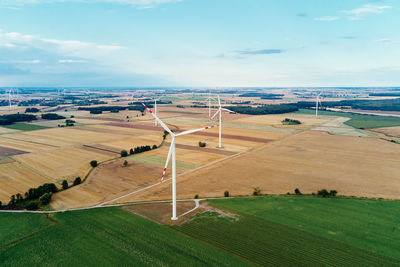 Windmill among agricultural fields. wind turbine generator at summer day