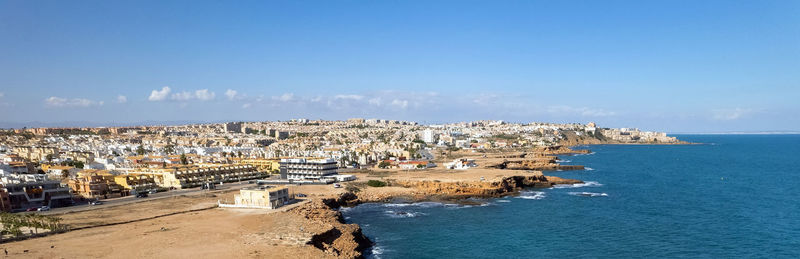 Aerial view of townscape by sea against sky