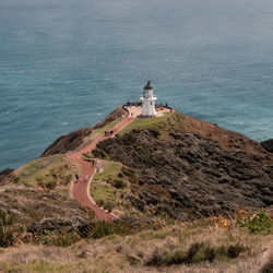 High angle view of lighthouse amidst sea and buildings