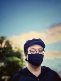 Portrait of young man wearing eyeglasses against sky