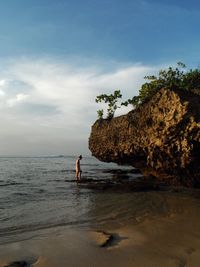 Woman standing on shore at beach against sky