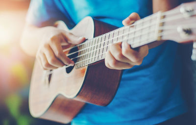 Midsection of man playing guitar