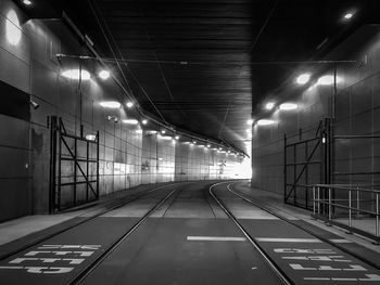 Empty road along illuminated lights at night