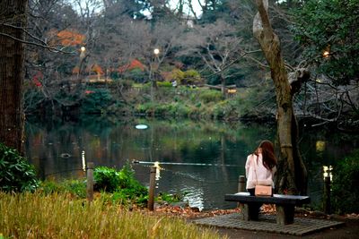 Rear view of woman sitting at lakeshore