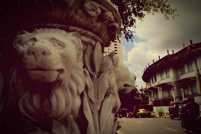 Statue in city against sky