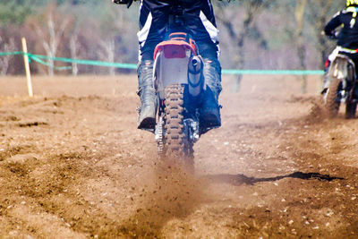 Low section of man riding motorcycle in motocross race on mud