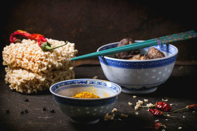 High angle view of raw noodles with turmeric and shiitake mushrooms on table