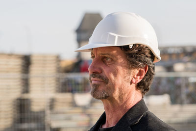 Close-up of thoughtful architect standing against buildings