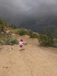 Rear view of boy walking on mountain against sky