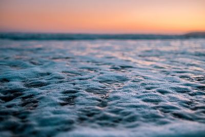 Surf on beach against orange sky