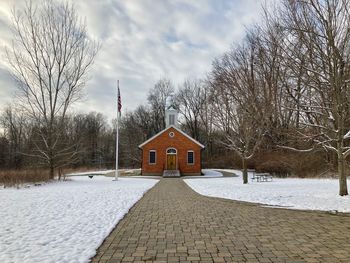 Bare trees by building against sky during winter