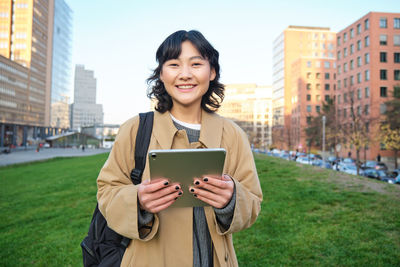 Portrait of young woman standing against trees