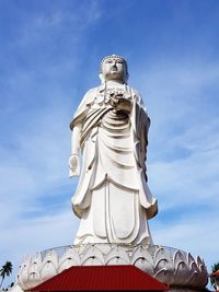 Low angle view of buddha statue against blue sky