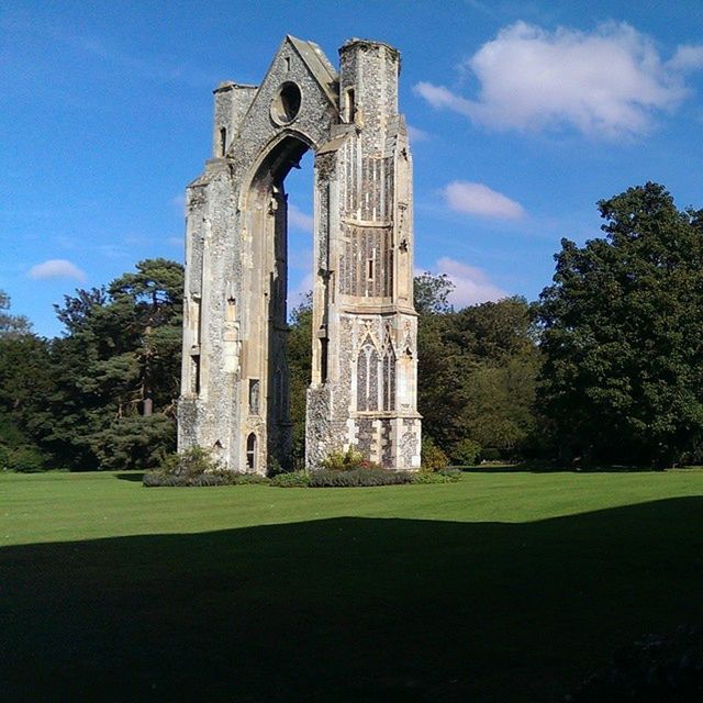 architecture, built structure, building exterior, tree, sky, grass, religion, church, history, low angle view, place of worship, spirituality, old, green color, lawn, day, the past, cloud - sky