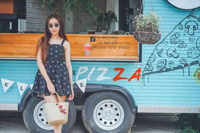 Young woman wearing sunglasses standing against food truck