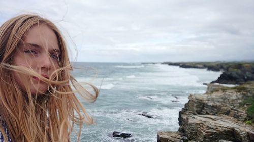 Portrait of teenage girl with tousled hair against sea at beach