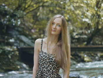 Portrait of beautiful young woman standing against tree