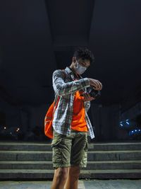 Full length of man standing against illuminated wall at night