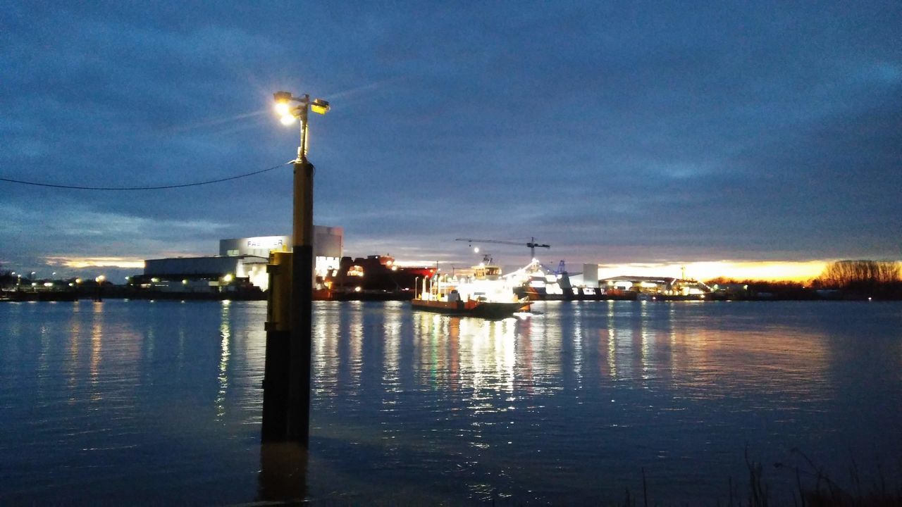 ILLUMINATED CITY BY SEA AGAINST SKY