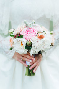 Midsection of bride holding bouquet