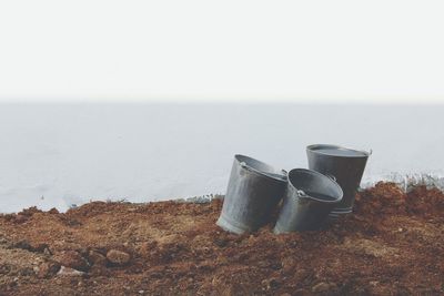 Close-up of buckets on field against sky