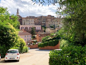 Cars on road by townscape against sky