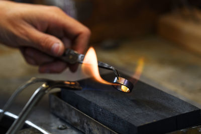 Cropped hand of manual worker heating metallic ring in factory