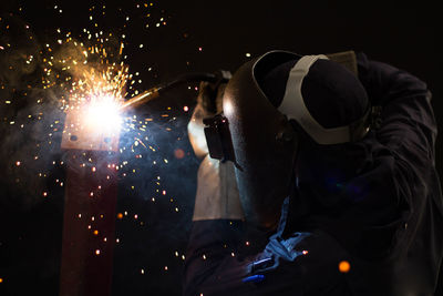 Man welding metal at night