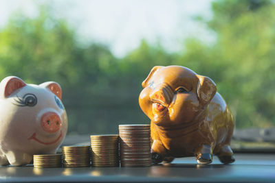 Stacked coins and piggy banks on table