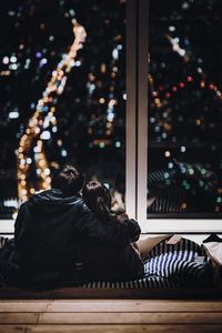 Rear view of woman with dog sitting at night