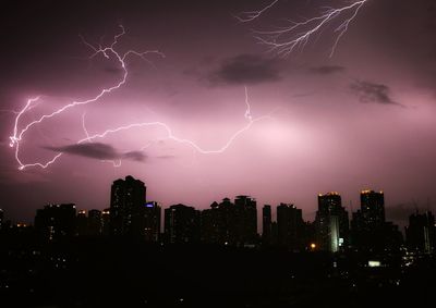 Firework display over city against sky at night