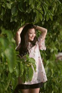 Young woman standing against plants at park