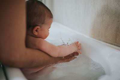 Midsection of woman with child in bathtub at home