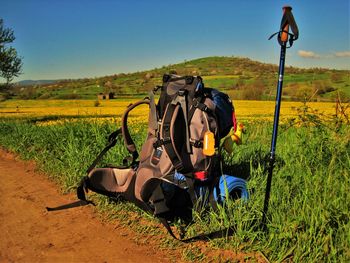 Backpack on grassy landscape against clear sky
