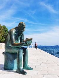 Statue by sea against sky